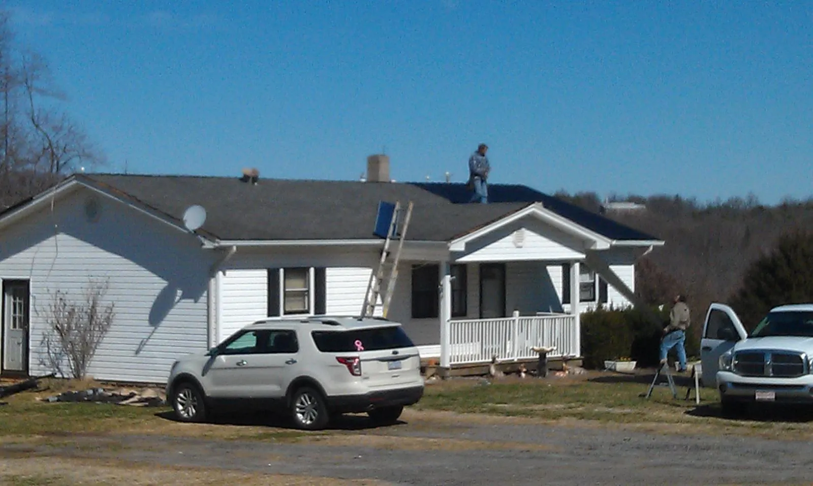 Roofers stripping shingles from a white ranch house roof in Mount Morris